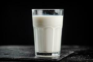 een glas van vers melk Aan een steen bord. foto