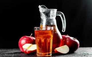 sap van rijp appels in een kruik en een glas Aan de tafel. foto