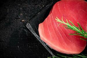 rauw tonijn Aan een steen bord met rozemarijn. foto