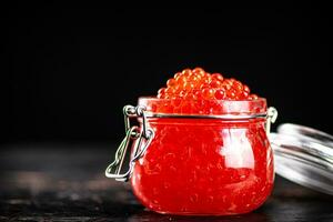 een Open glas pot vol van rood kaviaar. foto