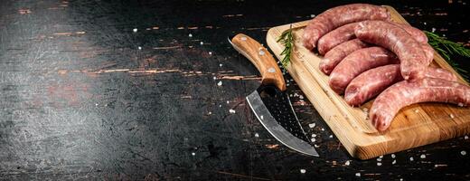 rauw worstjes Aan een snijdend bord met een mes en rozemarijn. foto