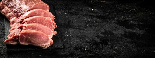 stukken van rauw varkensvlees Aan een steen bord. foto