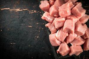 stukken van rauw varkensvlees Aan een snijdend bord Aan de tafel. foto
