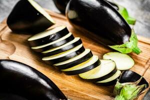 besnoeiing in stukken van rijp aubergine Aan een houten snijdend bord. foto