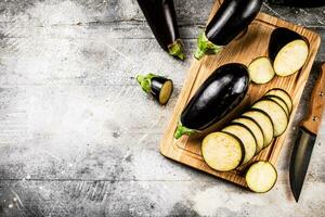 besnoeiing in stukken van rijp aubergine Aan een houten snijdend bord. foto