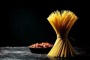 bolognese saus in een frituren pan met een bundel van pasta droog. foto