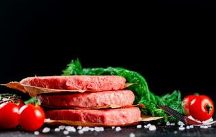 rauw hamburger Aan een tafel met Groenen en zout. foto
