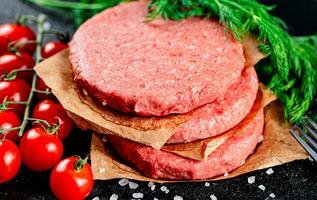 rauw hamburger Aan een tafel met Groenen en zout. foto