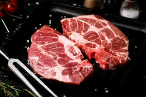 rauw varkensvlees steak in een frituren pan met baai bladeren en rozemarijn. foto