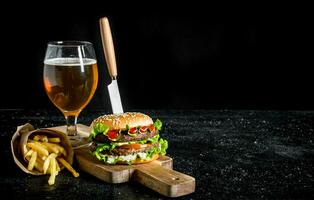 hamburger met een mes, friet, bier in een glas. foto