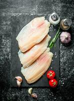 tilapia vis filet Aan een steen bord met tomaten, knoflook kruidnagel en specerijen. foto