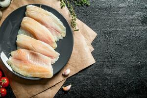 vis filet Aan bord met papier, tijm en knoflook kruidnagel. foto