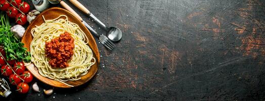 spaghetti met bolognese saus in een bord met tomaten, peterselie en knoflook. foto