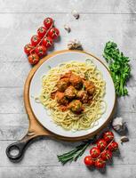 spaghetti en vlees ballen Aan een bord met tomaten, kruiden en knoflook. foto