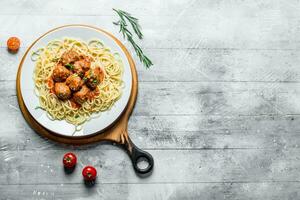 spaghetti met vlees ballen Aan een bord van rozemarijn en tomaten. foto