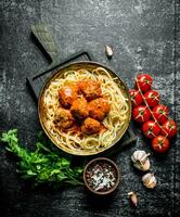 spaghetti en vlees ballen in pan met peterselie, tomaten en knoflook. foto