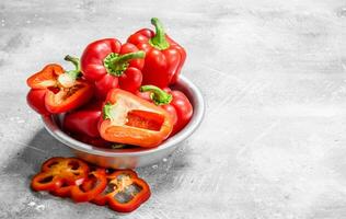 stukken van zoet peper en geheel rood paprika's in de schaal. foto