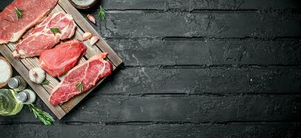 rauw vlees. varkensvlees en rundvlees steaks Aan een dienblad met specerijen en rozemarijn takje. foto