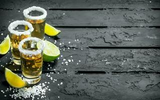 tequila in een schot glas met zout en plakjes van vers limoen. foto