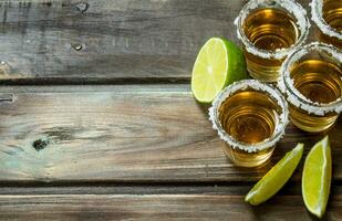 tequila in een schot glas met limoen plakjes. foto