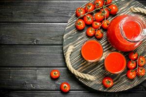 tomaat sap in een kruik en bril Aan dienblad. foto