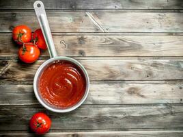 tomaat saus in een pan en rijp tomaten. foto