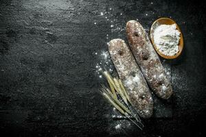 rogge brood met meel en aartjes Aan een steen bord. foto