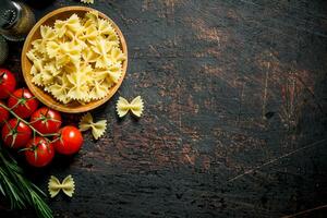 rauw farfalle pasta in een kom met de tomaten, rozemarijn, champignons en specerijen. foto