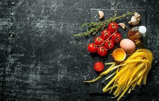 huis gemaakt rauw pasta met tijm, eieren, olie en tomaten. foto