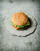 vers hamburger met kaas en vlees Aan een steen stellage. foto