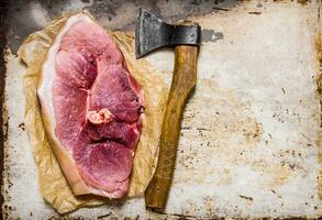 een groot stuk van rauw varkensvlees met een vlees bijl. foto