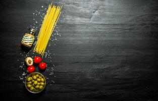 droog spaghetti met olijven, tomaten en zout. foto