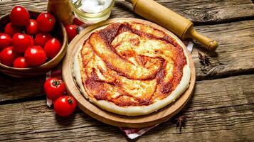 pizza deeg met tomaat saus, rollend pin en tomaten. foto