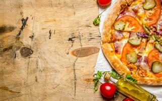 smakelijk pizza met spek en tomaten. Aan houten tafel. foto