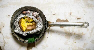 gebakken aardappelen in een pan Aan een oud rustiek tafel . foto