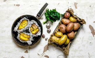 de concept van gebakken aardappel in folie Aan een oud rustiek tafel . foto