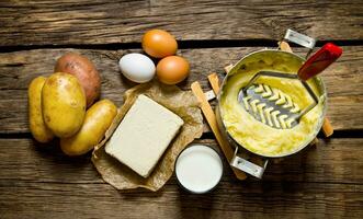 ingrediënten voor gepureerd aardappelen - eieren, melk, boter en aardappelen Aan houten achtergrond. foto