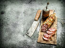 salami Aan een snijdend bord met een oud bijl. foto