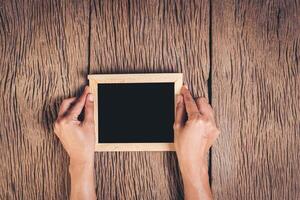 bovenaanzicht hand met schoolbord op hout achtergrond. foto