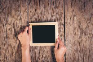 bovenaanzicht hand met schoolbord op hout achtergrond. foto