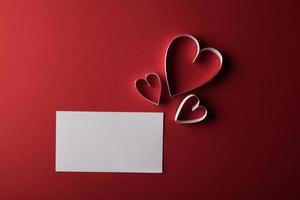 rood hartpapier en blanco met notitiekaart op rode achtergrond.