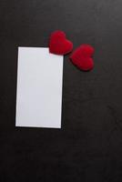rood hartpapier en blanco met notitiekaart op muurachtergrond. foto