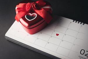 rood hart in 14 februari op de kalender met hartvormige geschenkdoos. foto