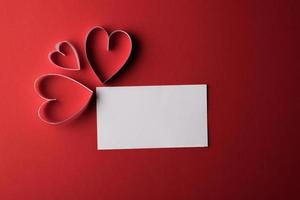 rood hartpapier en blanco met notitiekaart op rode achtergrond.