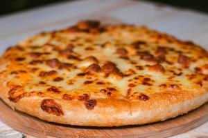 close-up selectieve focus van de klaar om pizza te eten op een houten dienblad foto