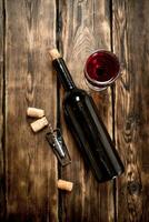 fles van rood wijn met een kurketrekker en kurken. foto