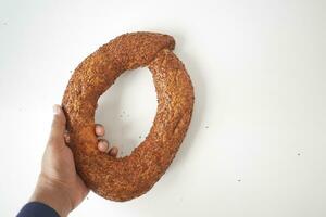top visie van hand- Holding een Turks bagel simit Aan tafel foto
