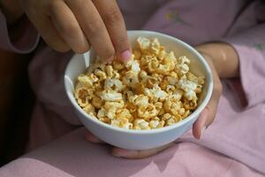 de meisje bereikt voor de popcorn in een kom foto