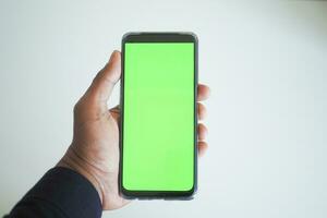 pov schot van jong Mens hand- gebruik makend van slim telefoon met groen scherm foto