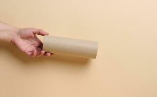 een vrouw hand- houdt een bruin papier buis van papier handdoeken foto